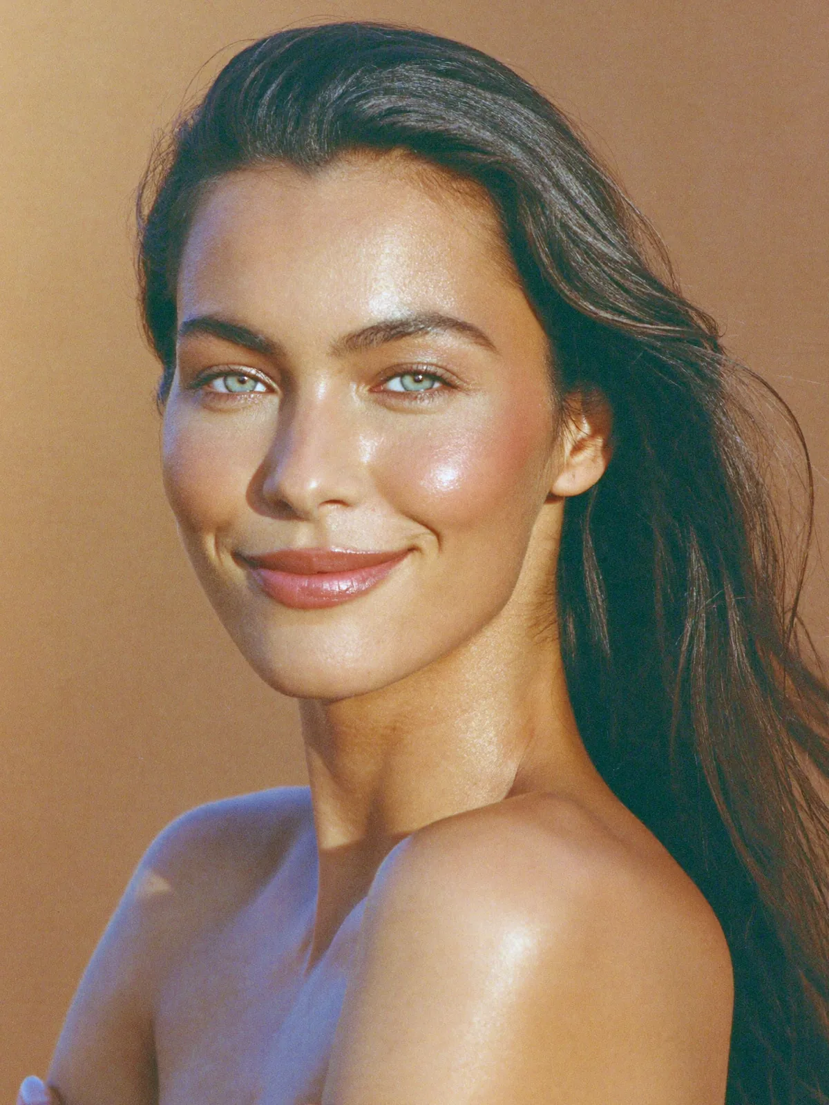 A woman turned over her shoulder in warm light, smiling, looking well